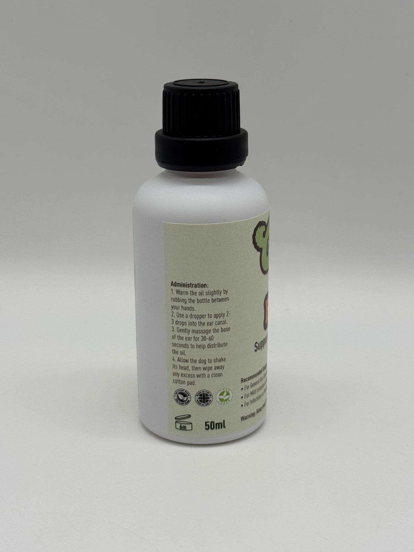 Image of Canine Holistics™ natural ear oil for dogs in a white glass bottle with dripper nozzle and a black lid. Left side view of branded product displaying instructions for use. 