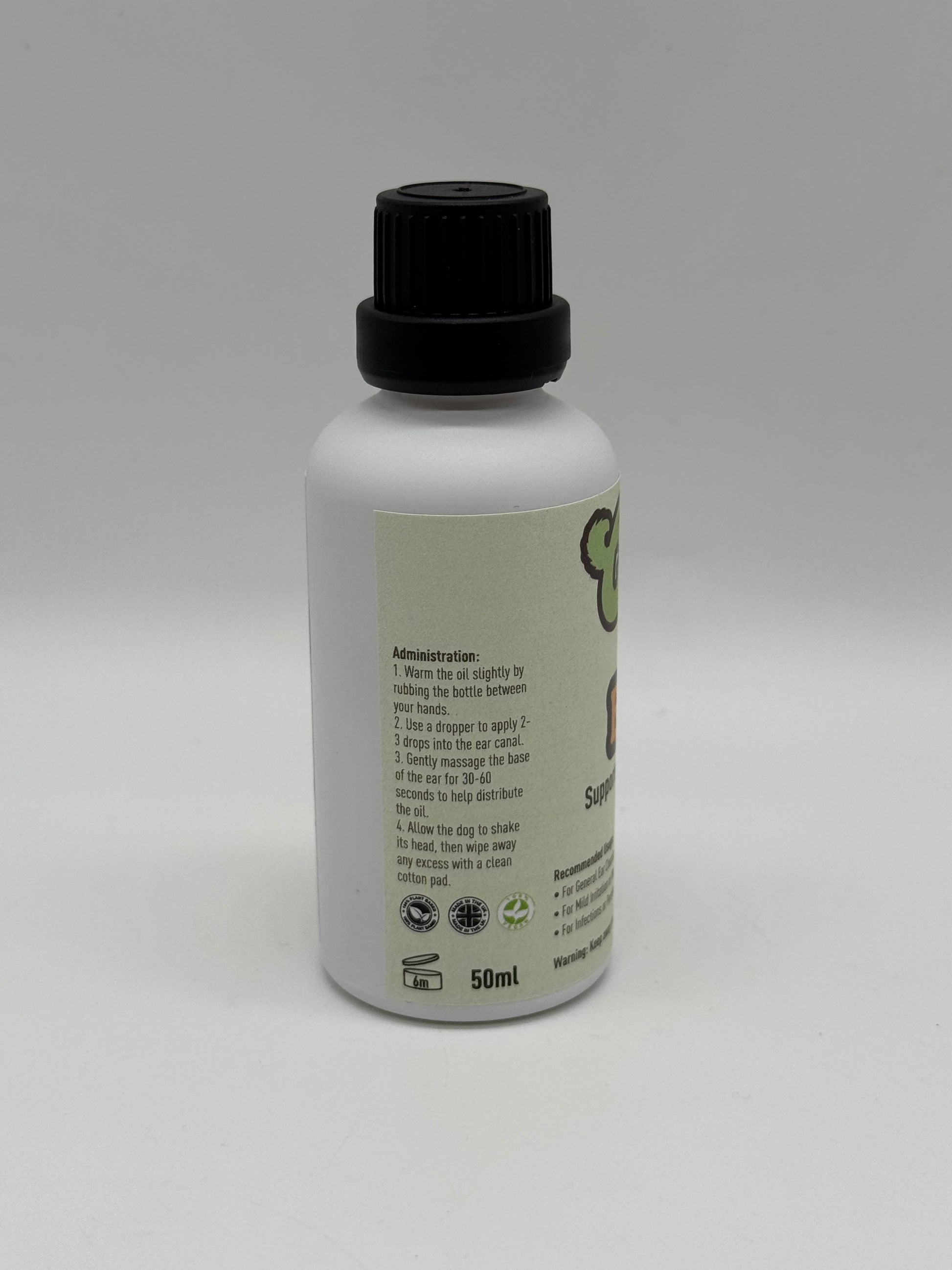 Image of Canine Holistics™ natural ear oil for dogs in a white glass bottle with dripper nozzle and a black lid. Left side view of branded product displaying instructions for use. 