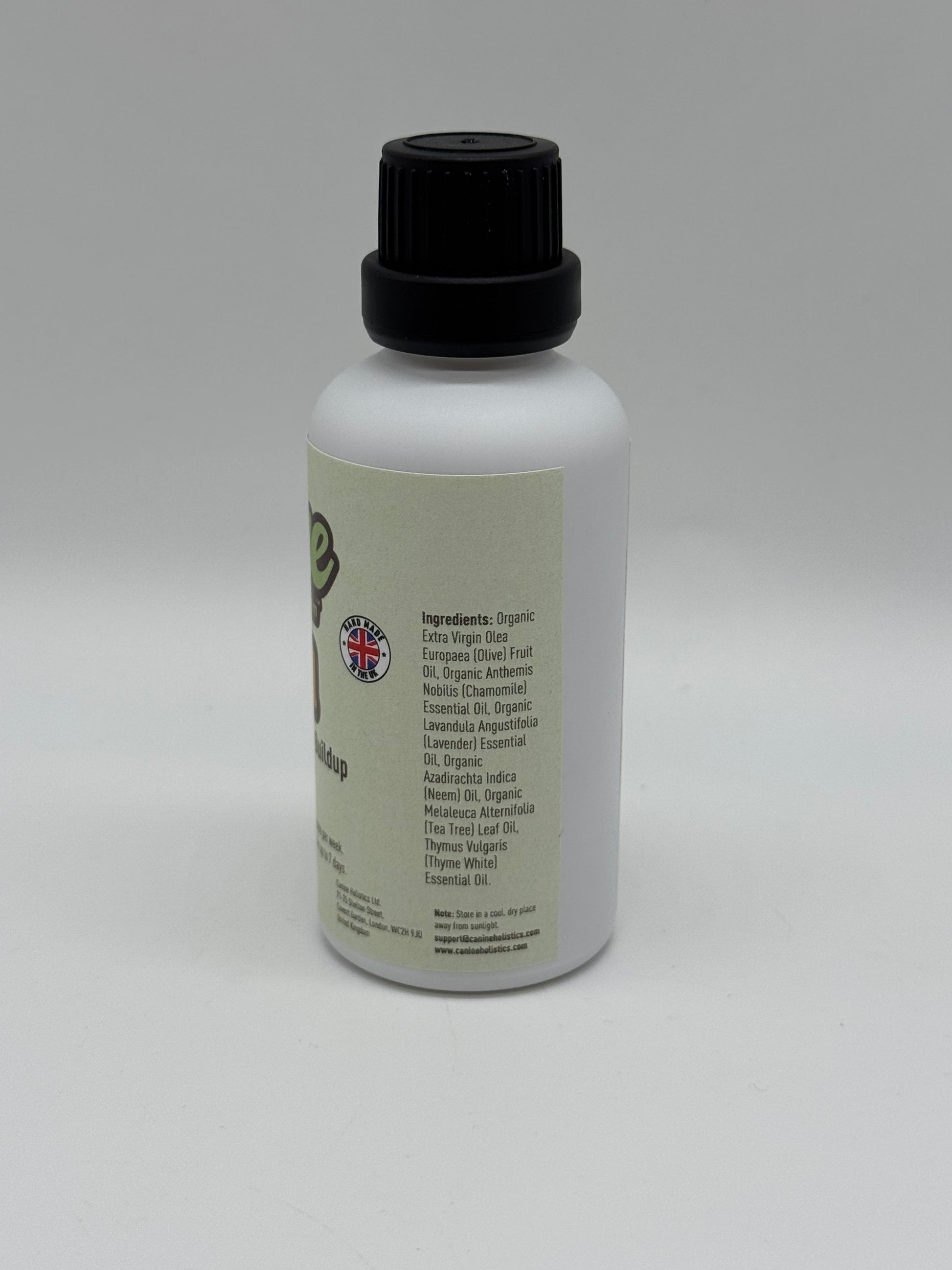 Image of Canine Holistics™ natural ear oil for dogs in a white glass bottle with dripper nozzle and a black lid. Right side view of branded product displaying list of ingredients. 